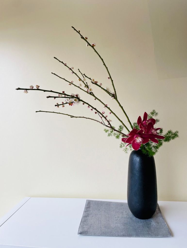 Tall ikebana arrangement with flowers and branches